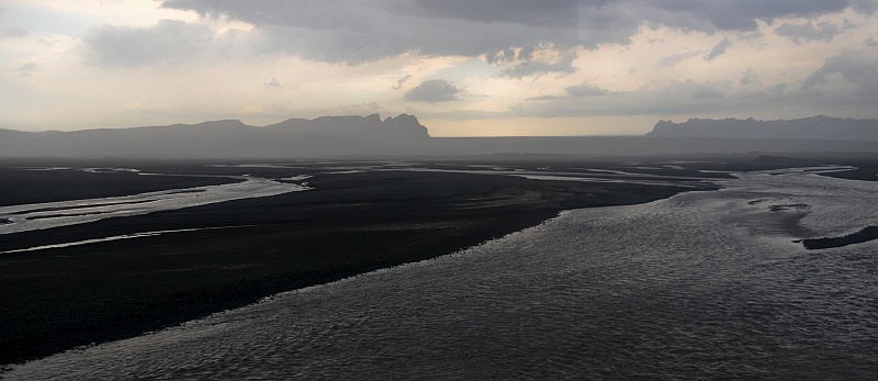 ABC_5971.jpg - Les sandurs, des immenses �tendues de sable noir qui s'�talent au pied du glacier Vatnaj�kull et qui sont le r�sultat des d�bacles qui ravagent le Sud quand le volcan Grimsvotn se r�veille sous la calotte glaciaire. On distingue au loin la langue glaciaire toute noire du Skeidararjokull d'o� surgissent les crues.