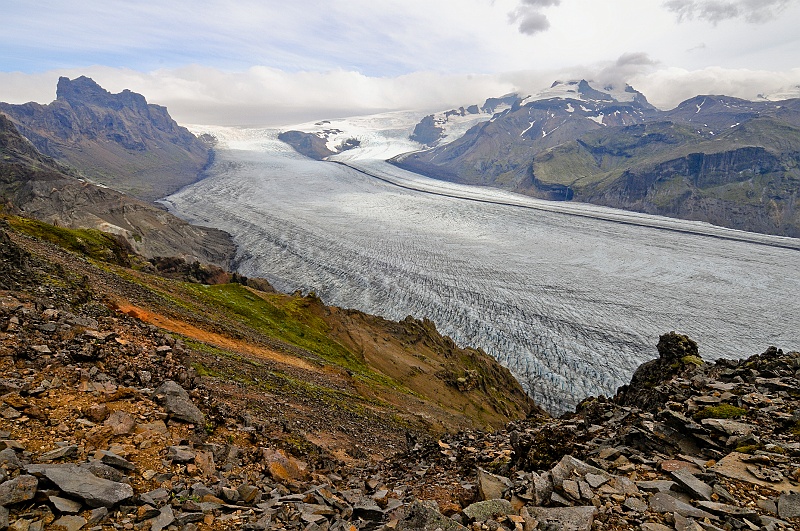 ABC_6026.jpg - Le point de vue de Sjonarnipa surplombe la langue glaciaire du Skaftafellsj�kull et ses seracs stri�s de moraines noires. Au centre de la langue glaci�re, on voit une ligne noire qui est une moraine centrale. C'est l� que se rejoignent les d�bris pouss�s les deux langues glaci�res.